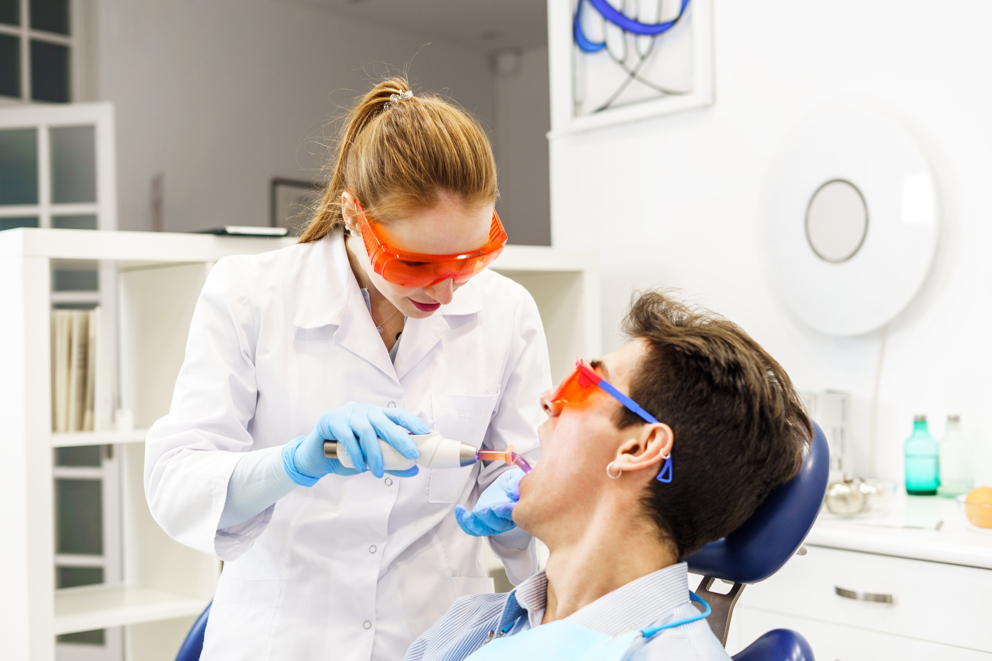 Woman healing teeth of patient in clinic
